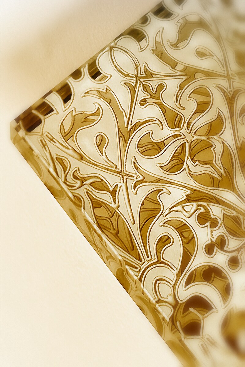 Macro detail of an etched Art Nouveau pattern carved into bronze-tinted architectural glass